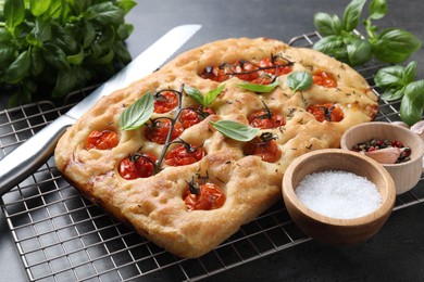 Photo of Delicious focaccia with tomatoes, spices and knife on table, closeup