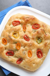 Photo of Delicious focaccia with tomatoes and rosemary on table, top view