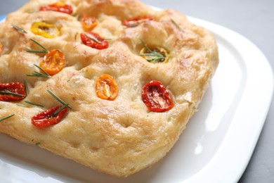 Photo of Delicious focaccia with tomatoes and rosemary on table, closeup