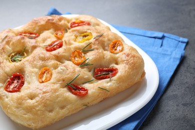 Photo of Delicious focaccia with tomatoes and rosemary on table, closeup