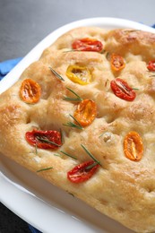 Photo of Delicious focaccia with tomatoes and rosemary on table, closeup