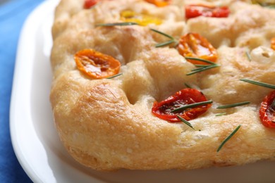 Photo of Delicious focaccia with tomatoes and rosemary on table, closeup