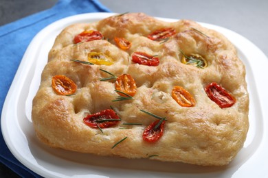 Photo of Delicious focaccia with tomatoes and rosemary on table, closeup