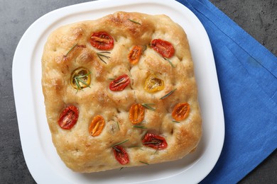 Photo of Delicious focaccia with tomatoes and rosemary on gray table, top view