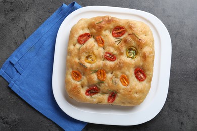 Photo of Delicious focaccia with tomatoes and rosemary on gray textured table, top view