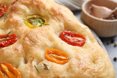 Photo of Delicious focaccia with tomatoes and rosemary on table, closeup