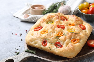 Photo of Delicious focaccia with tomatoes and spices on gray table, closeup
