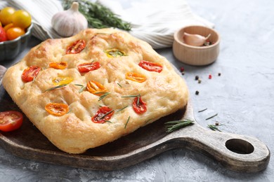 Photo of Delicious focaccia with tomatoes and spices on gray textured table, closeup