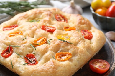 Photo of Delicious focaccia with tomatoes and rosemary on table, closeup
