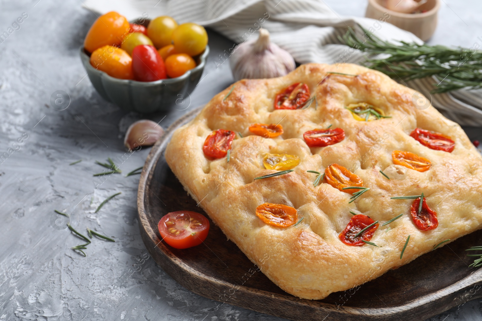 Delicious focaccia with tomatoes and spices on gray textured table, closeup Photo of Delicious focaccia with tomatoes and spices on gray textured table, closeup