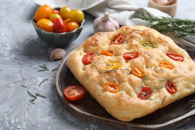 Photo of Delicious focaccia with tomatoes and spices on gray textured table, closeup
