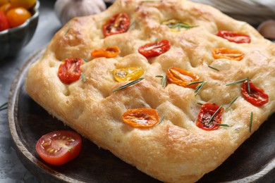 Photo of Delicious focaccia with tomatoes and rosemary on table, closeup