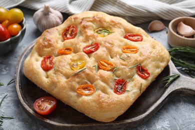 Photo of Delicious focaccia with tomatoes and spices on table, closeup