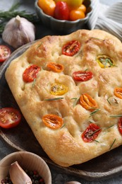 Photo of Delicious focaccia with tomatoes and spices on table, closeup