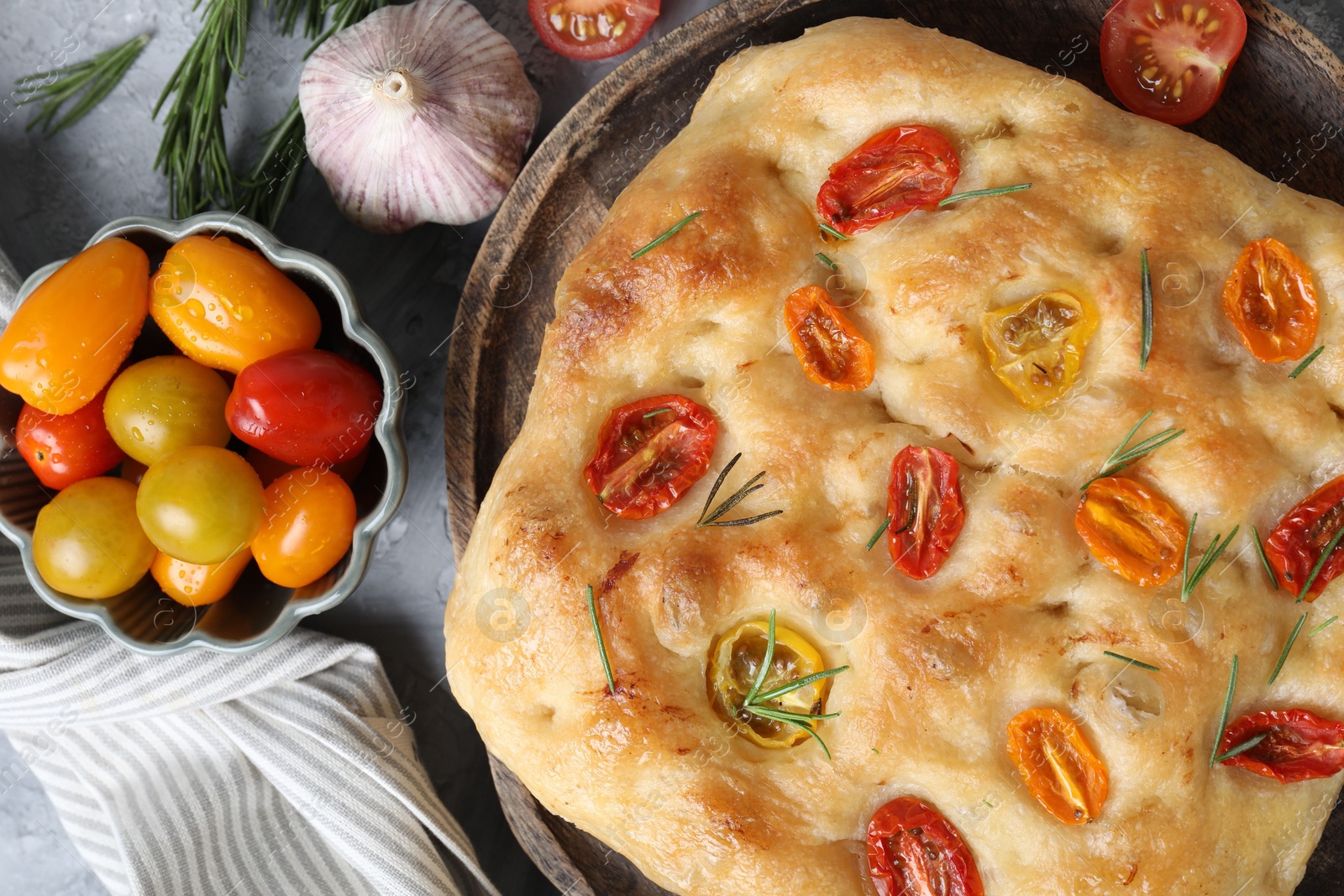 Delicious focaccia with tomatoes and spices on table, flat lay Photo of Delicious focaccia with tomatoes and spices on table, flat lay