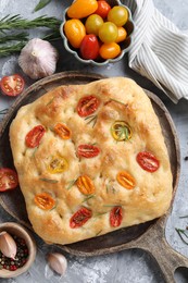 Photo of Delicious focaccia with tomatoes and spices on gray textured table, flat lay