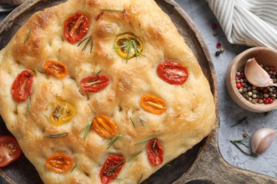 Photo of Delicious focaccia with tomatoes and spices on gray table, flat lay