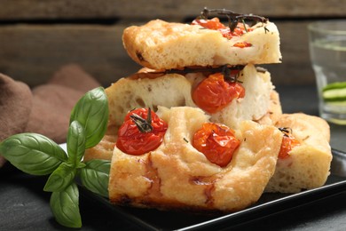 Photo of Pieces of delicious focaccia with tomatoes and spices on table, closeup