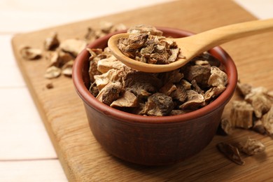 Photo of Pieces of dry chicory roots in bowl and spoon on table, closeup