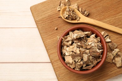 Photo of Pieces of dry chicory roots in bowl and spoon on wooden table, top view