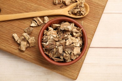 Photo of Pieces of dry chicory roots in bowl and spoon on wooden table, top view