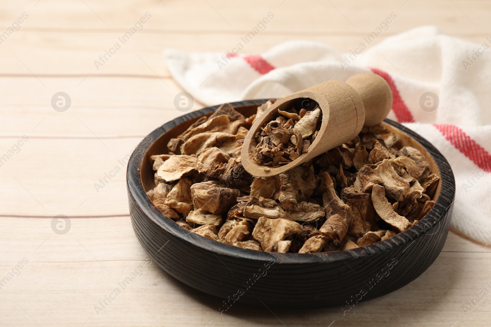 Pieces of dry chicory roots in bowl and scoop on wooden table, closeup Photo of Pieces of dry chicory roots in bowl and scoop on wooden table, closeup