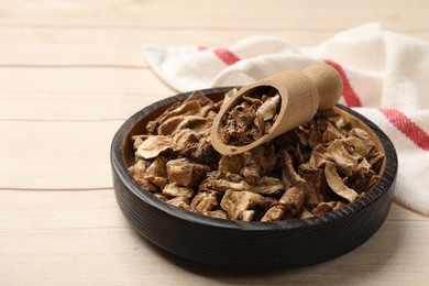 Photo of Pieces of dry chicory roots in bowl and scoop on wooden table, closeup