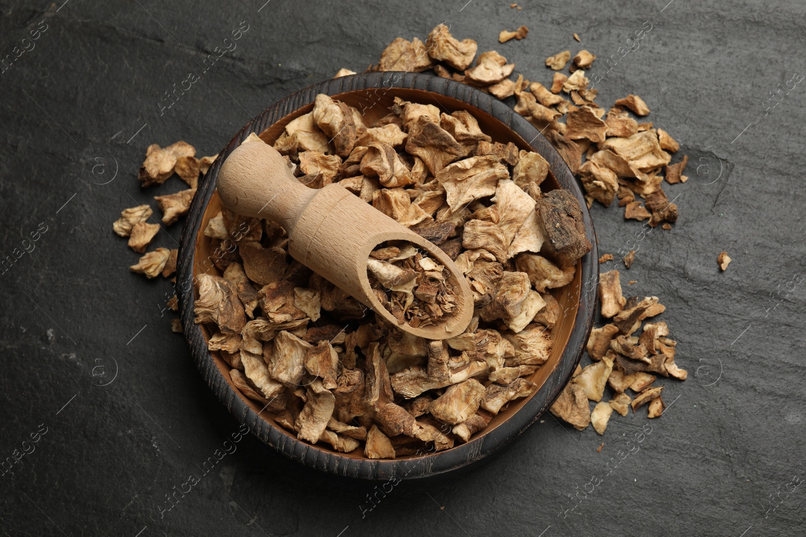 Pieces of dry chicory roots in bowl and scoop on dark textured table, top view Photo of Pieces of dry chicory roots in bowl and scoop on dark textured table, top view