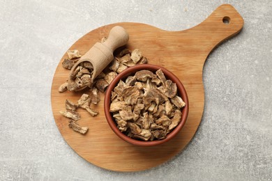 Photo of Pieces of dry chicory roots in bowl and scoop on gray textured table, top view