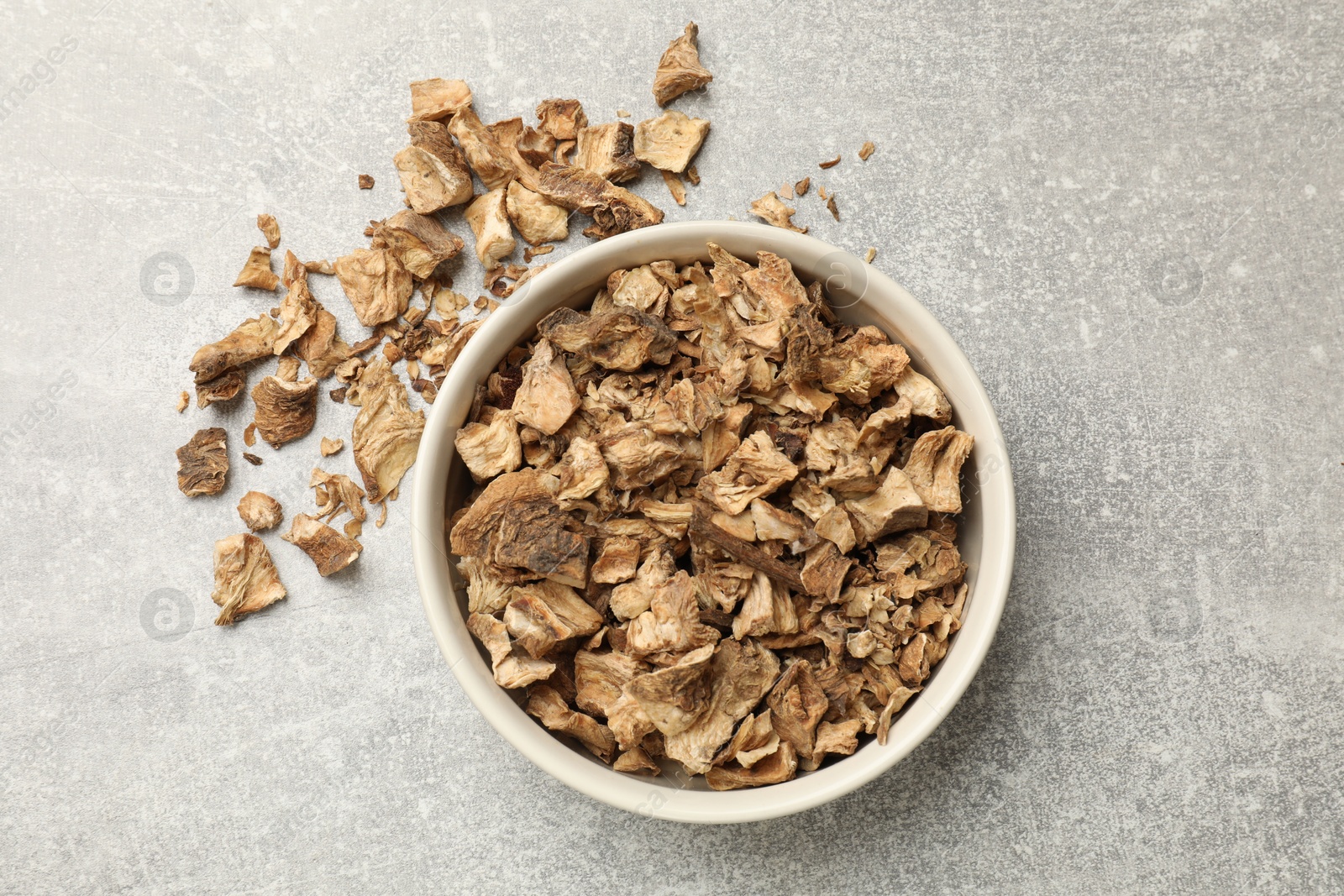 Pieces of dry chicory roots in bowl on gray textured table, top view Photo of Pieces of dry chicory roots in bowl on gray textured table, top view