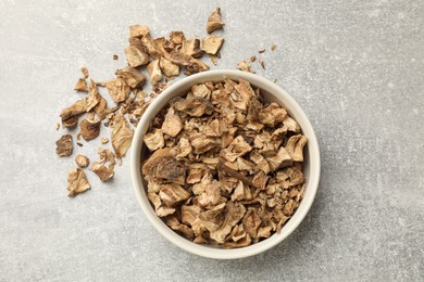 Photo of Pieces of dry chicory roots in bowl on gray textured table, top view