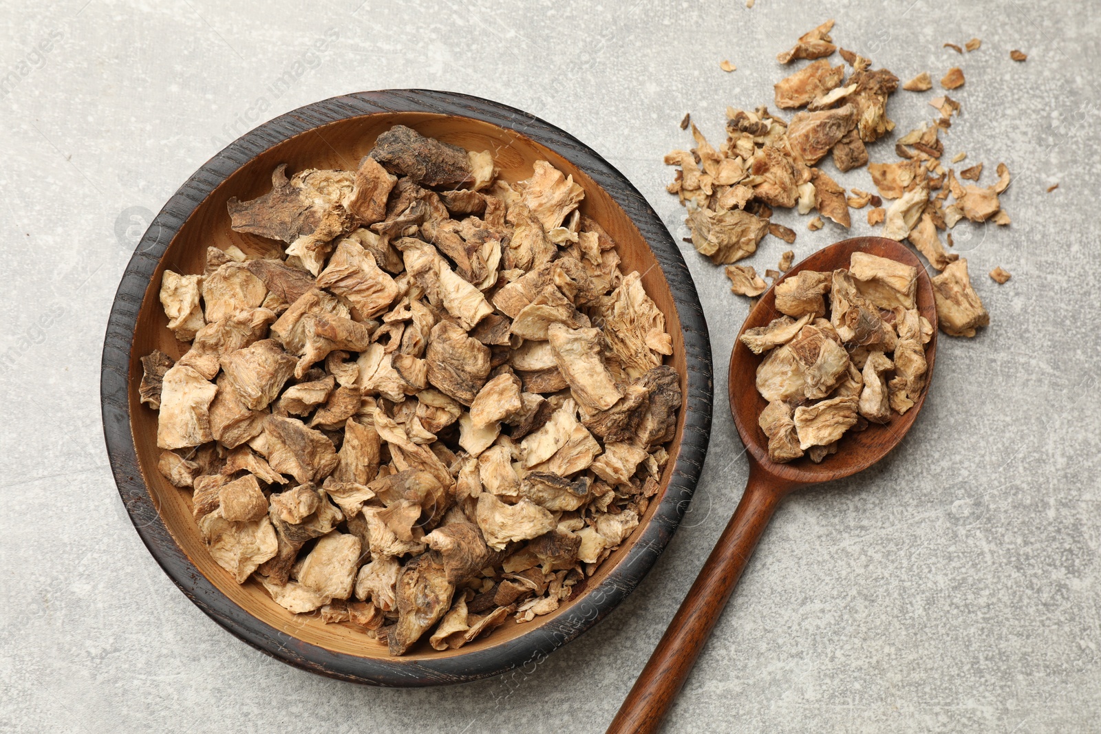 Pieces of dry chicory roots in bowl and spoon on gray textured table, flat lay Photo of Pieces of dry chicory roots in bowl and spoon on gray textured table, flat lay