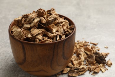 Photo of Pieces of dry chicory roots in bowl on gray table, closeup