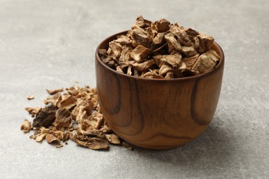 Photo of Pieces of dry chicory roots in bowl on gray textured table, closeup