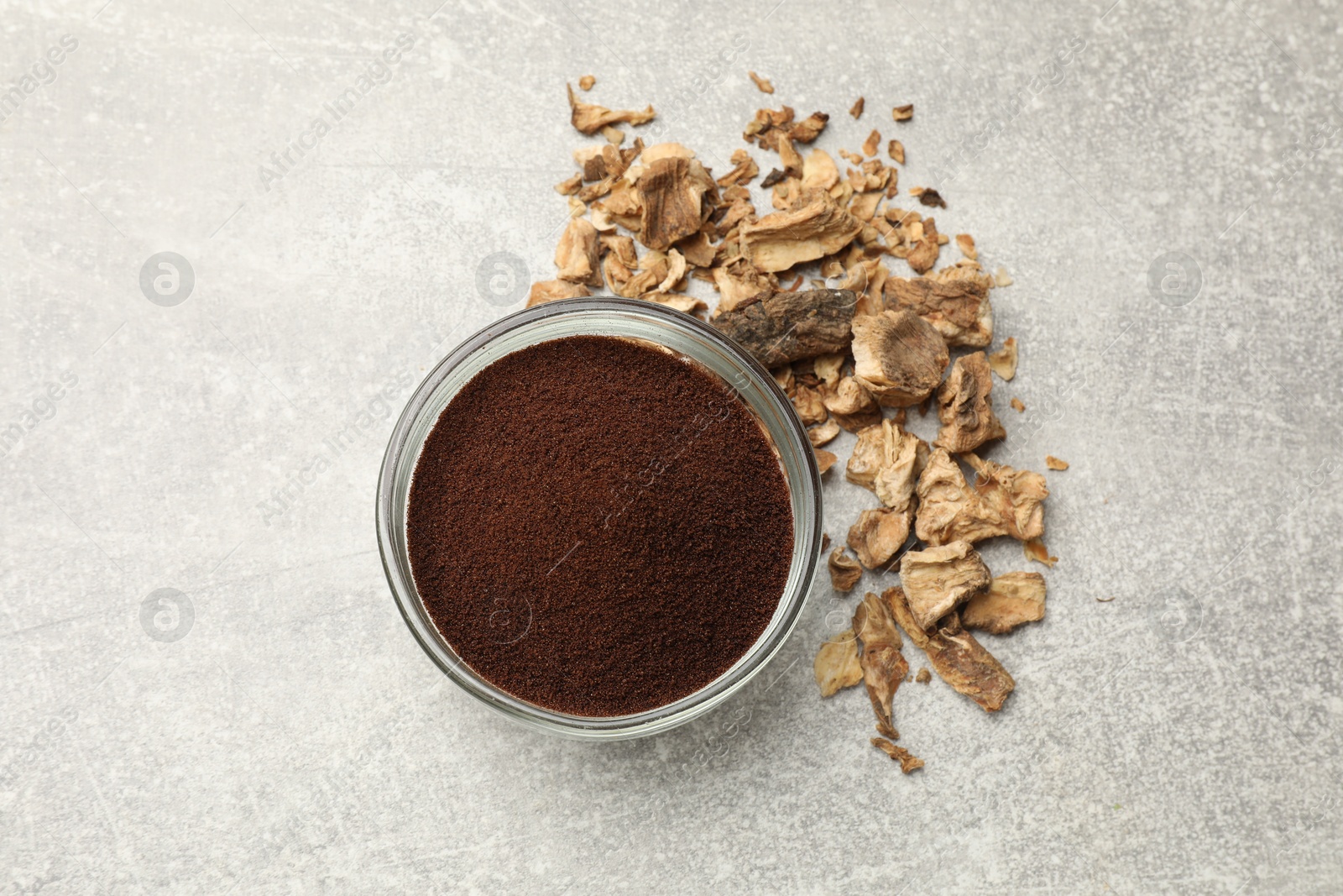 Chicory powder in bowl and pieces of dry roots on gray textured table, flat lay Photo of Chicory powder in bowl and pieces of dry roots on gray textured table, flat lay