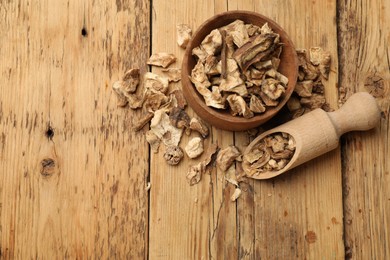 Photo of Pieces of dry chicory roots in bowl and scoop on wooden table, flat lay. Space for text