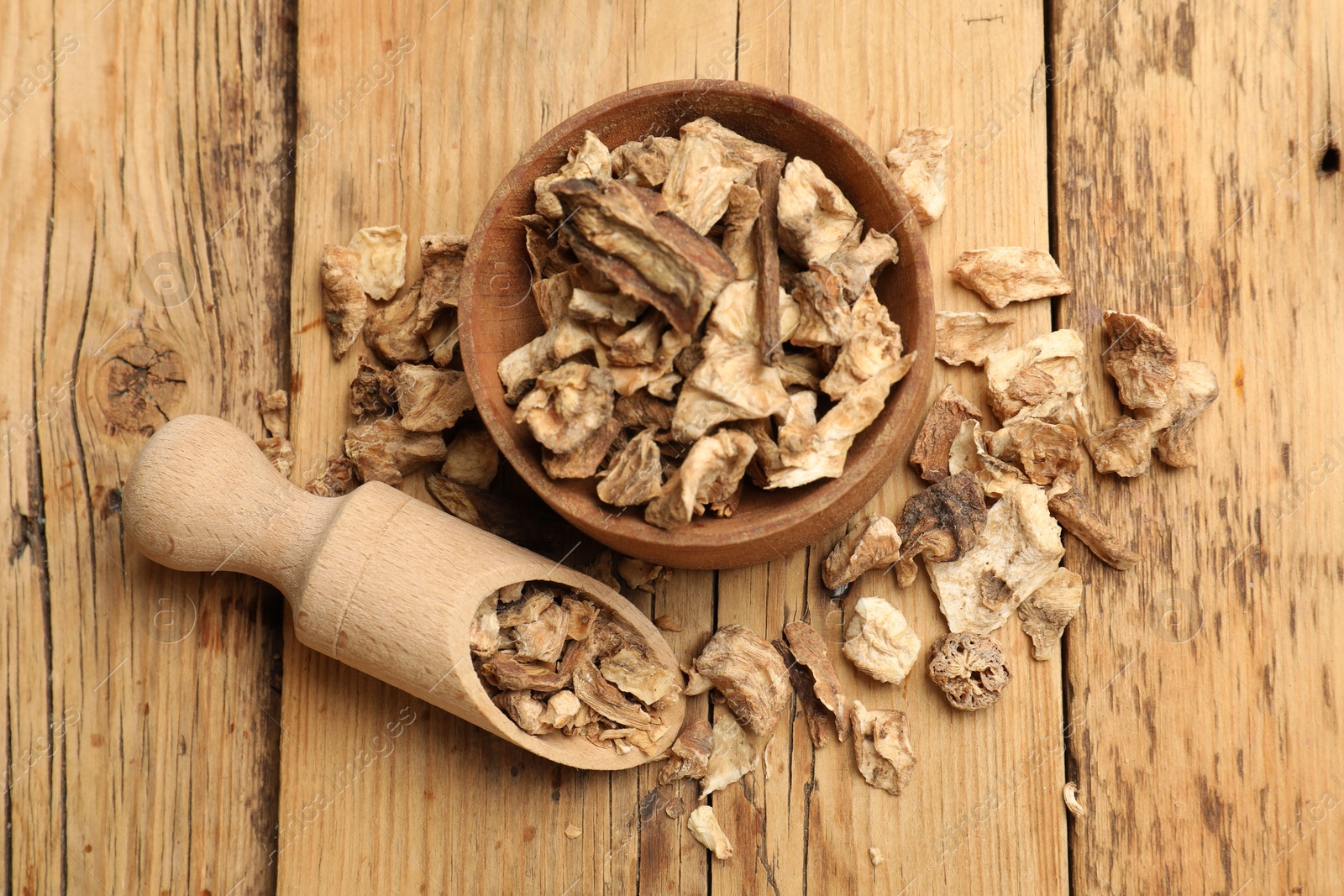 Pieces of dry chicory roots in bowl and scoop on wooden table, flat lay Photo of Pieces of dry chicory roots in bowl and scoop on wooden table, flat lay