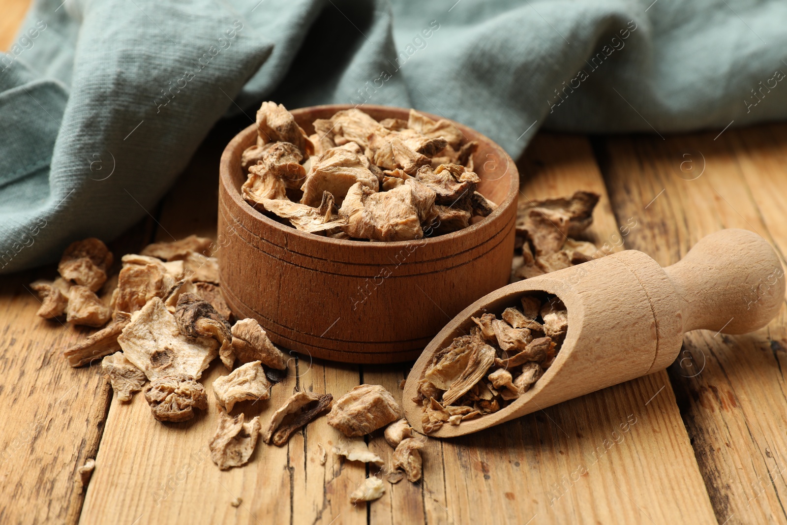 Pieces of dry chicory roots in bowl and scoop on wooden table, closeup Photo of Pieces of dry chicory roots in bowl and scoop on wooden table, closeup