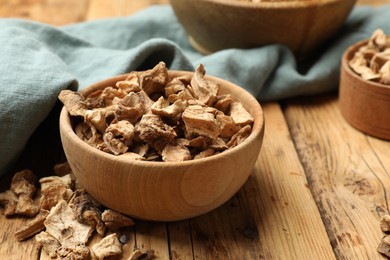 Photo of Pieces of dry chicory roots in bowl on wooden table, closeup