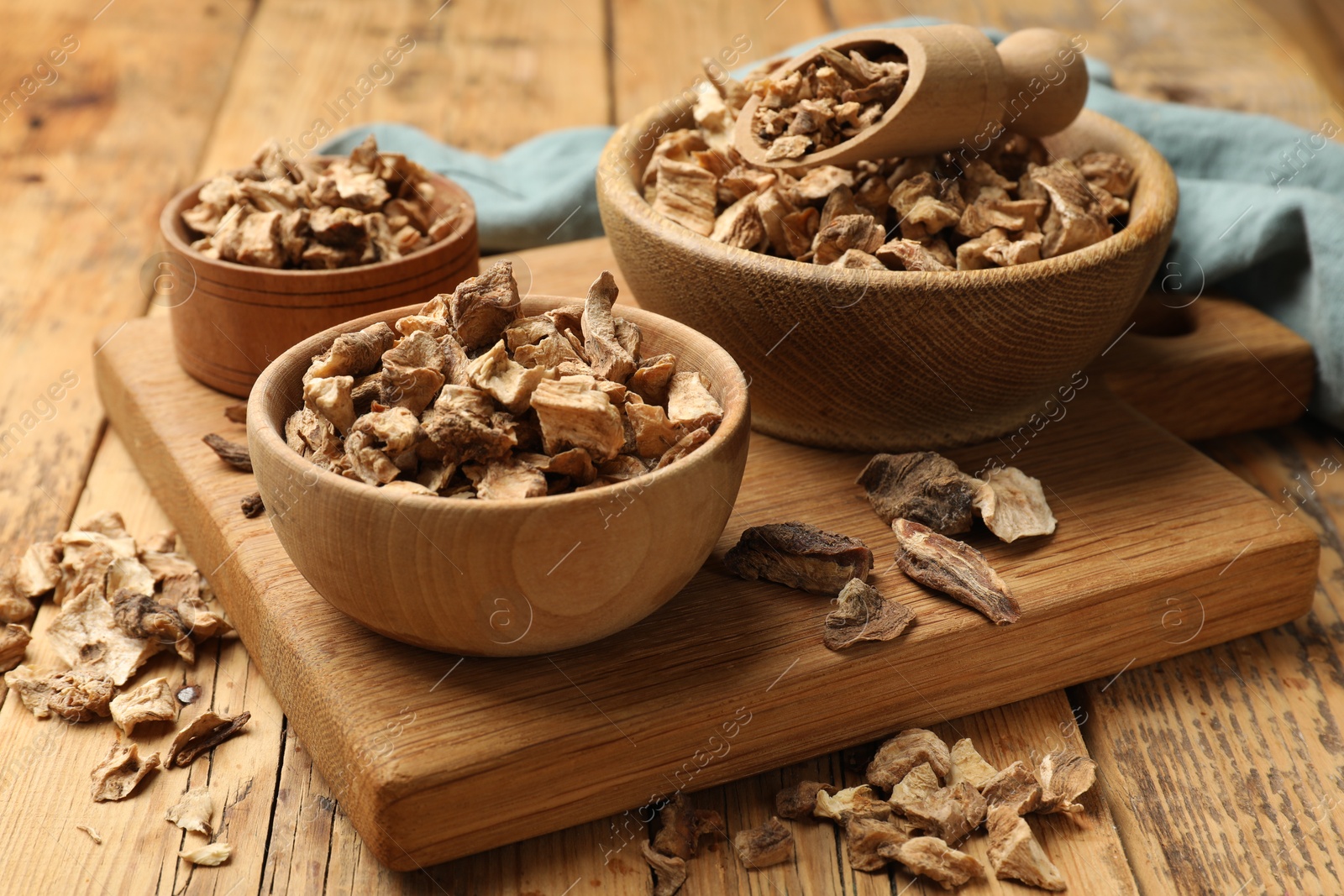 Pieces of dry chicory roots in bowls and scoop on wooden table Photo of Pieces of dry chicory roots in bowls and scoop on wooden table