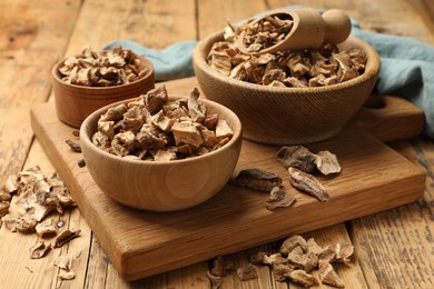 Photo of Pieces of dry chicory roots in bowls and scoop on wooden table