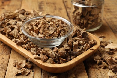 Photo of Pieces of dry chicory roots in bowl and jar on wooden table, closeup