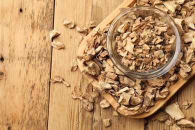 Photo of Pieces of dry chicory roots in bowl on wooden table, top view. Space for text
