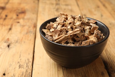 Photo of Pieces of dry chicory roots in bowl on wooden table, closeup