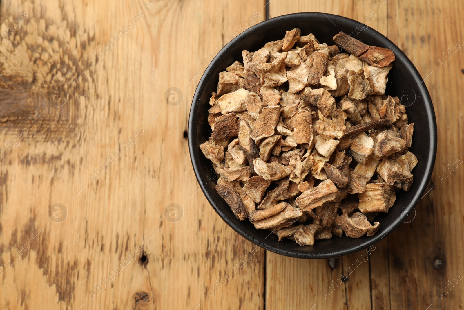 Pieces of dry chicory roots in bowl on wooden table, top view. Space for text Photo of Pieces of dry chicory roots in bowl on wooden table, top view. Space for text