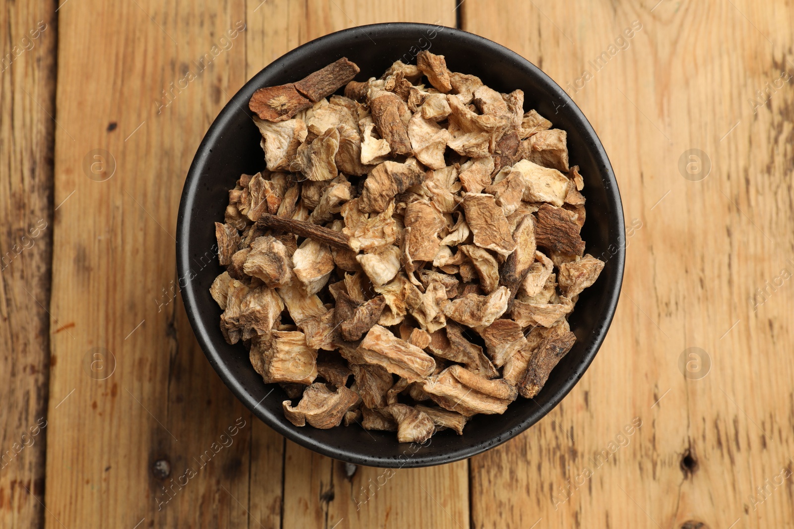 Pieces of dry chicory roots in bowl on wooden table, top view Photo of Pieces of dry chicory roots in bowl on wooden table, top view