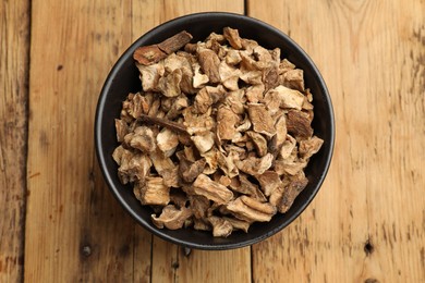 Photo of Pieces of dry chicory roots in bowl on wooden table, top view