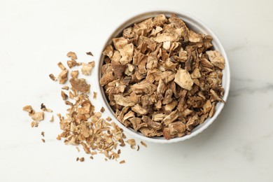 Photo of Pieces of dry chicory roots in bowl on white table, top view