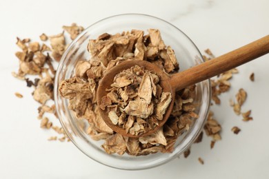 Photo of Pieces of dry chicory roots in bowl and spoon on white table, top view