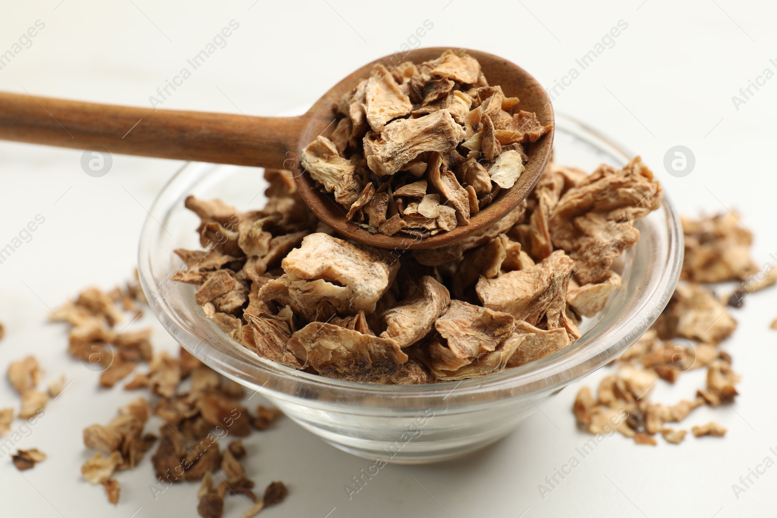 Pieces of dry chicory roots in bowl and spoon on white table, closeup Photo of Pieces of dry chicory roots in bowl and spoon on white table, closeup